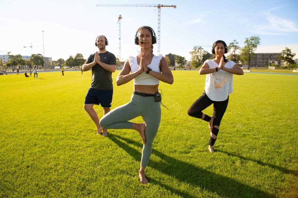 Drei Teilnehmer eines Yogakurses beim Training auf dem Rasenplatz der FRANKLIN Sportanlage